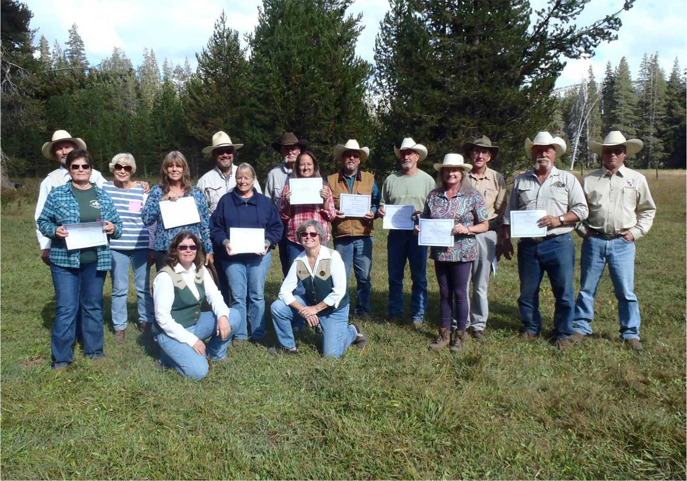 color photo of 16 Wilderness Riders holding
          certificates of completion (Stacy Kuhns and Donna Maier wearing Wilderness Rider vests in
          front row)